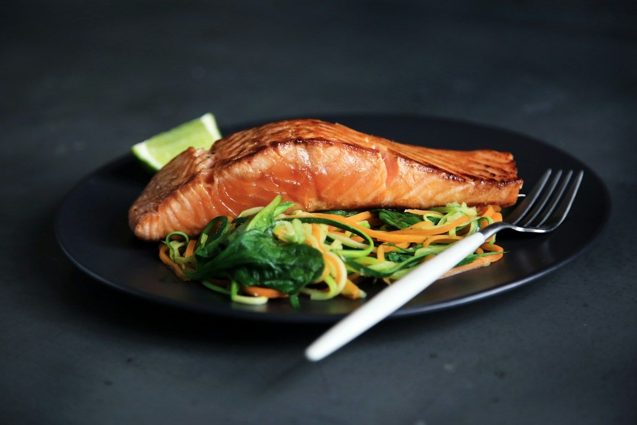 Salmon fillet on a dark plate with vegetables; illustrative seafood photograph